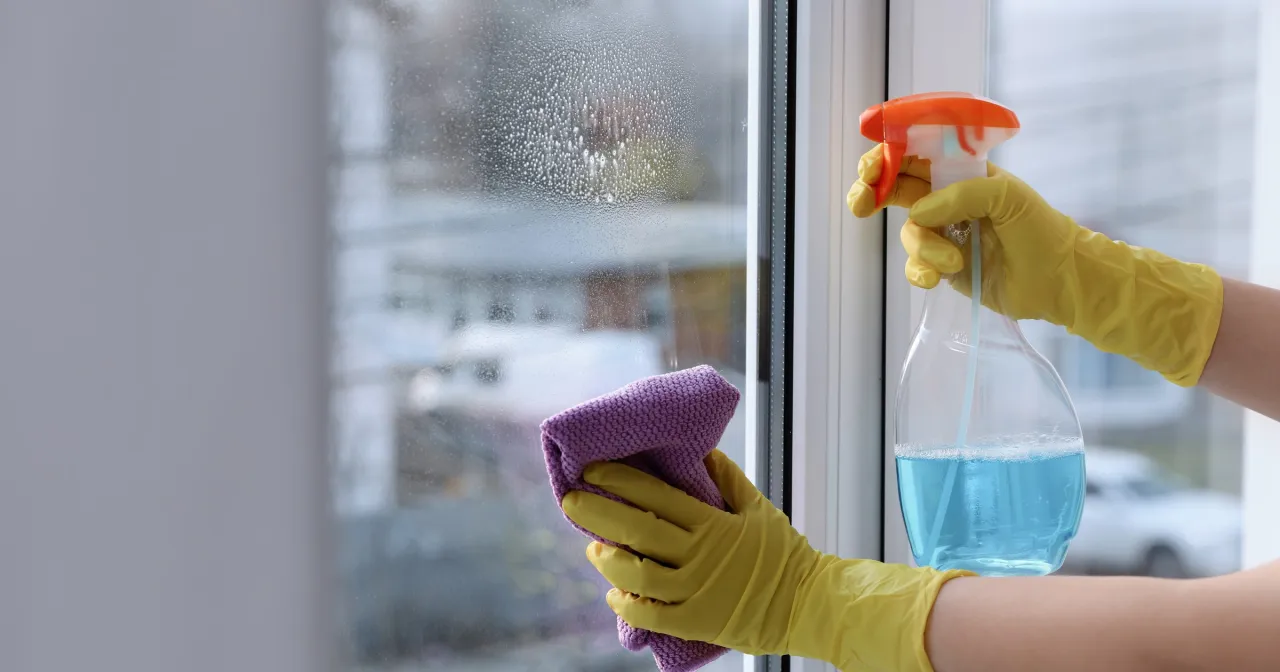 Ręce w żółtych rękawiczkach myją okno. Czy w ciąży można myć okna? Tak, jeśli czujesz się dobrze i masz pomoc.