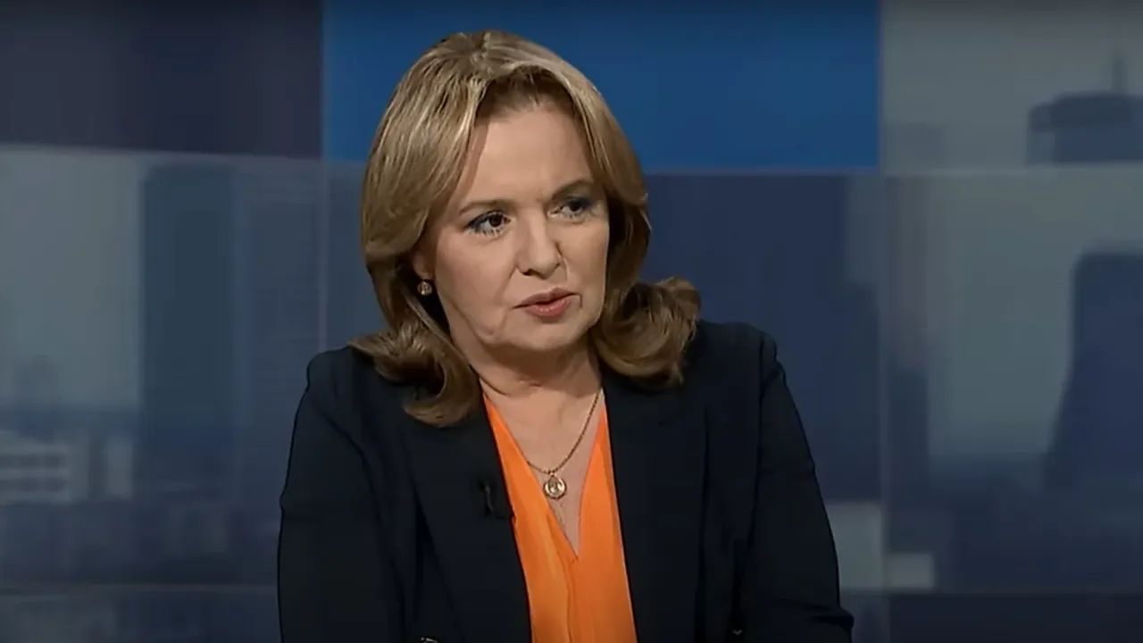 Dziennikarka TV Republika w pomarańczowej bluzce i granatowej marynarce, z wisiorkiem na szyi, udziela wywiadu.