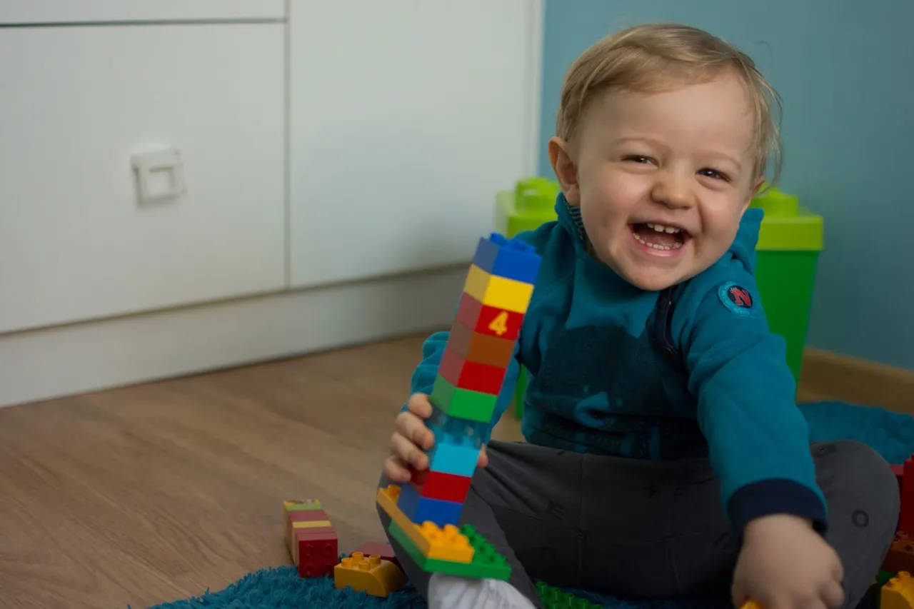 Dziecko buduje wieżę z kulko-klock&oacute;w, kreatywna zabawa