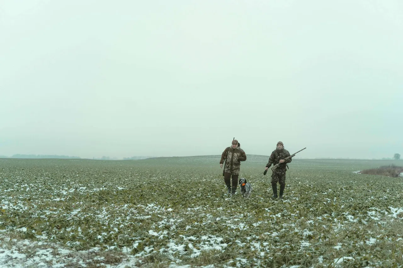 Dwóch myśliwych z psem przemierza zaśnieżone pole. To, co powinien wiedzieć myśliwy, to cierpliwość i obserwacja.