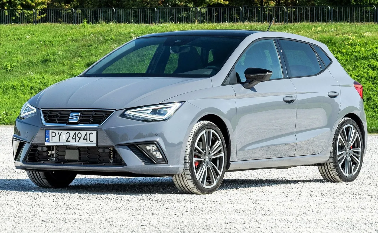 Szary Seat Ibiza, idealny na pierwsze auto, prezentuje się stylowo na żwirowej drodze.