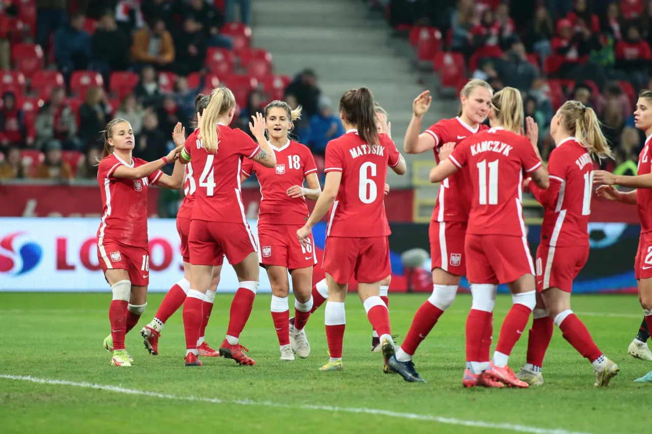 Piłkarki reprezentacji Polski w piłce nożnej świętują zwycięstwo. Widać numery 10, 34, 18, 6, 11, 16, 2.