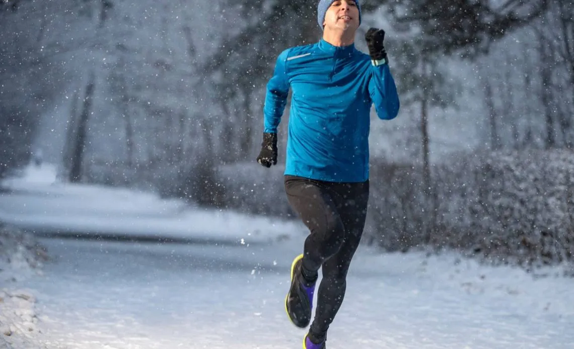 Biegacz w zimowym stroju na śniegu z termometrem