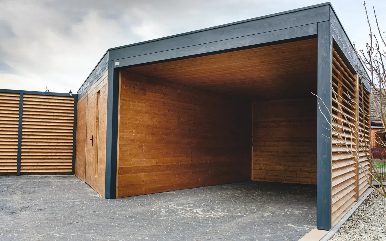 Nowoczesne wiaty garażowe drewniane z ciemnoszarą ramą i ażurowymi panelami bocznymi.