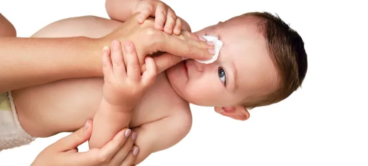 rodzic przemywający oko niemowlaka solą fizyczną