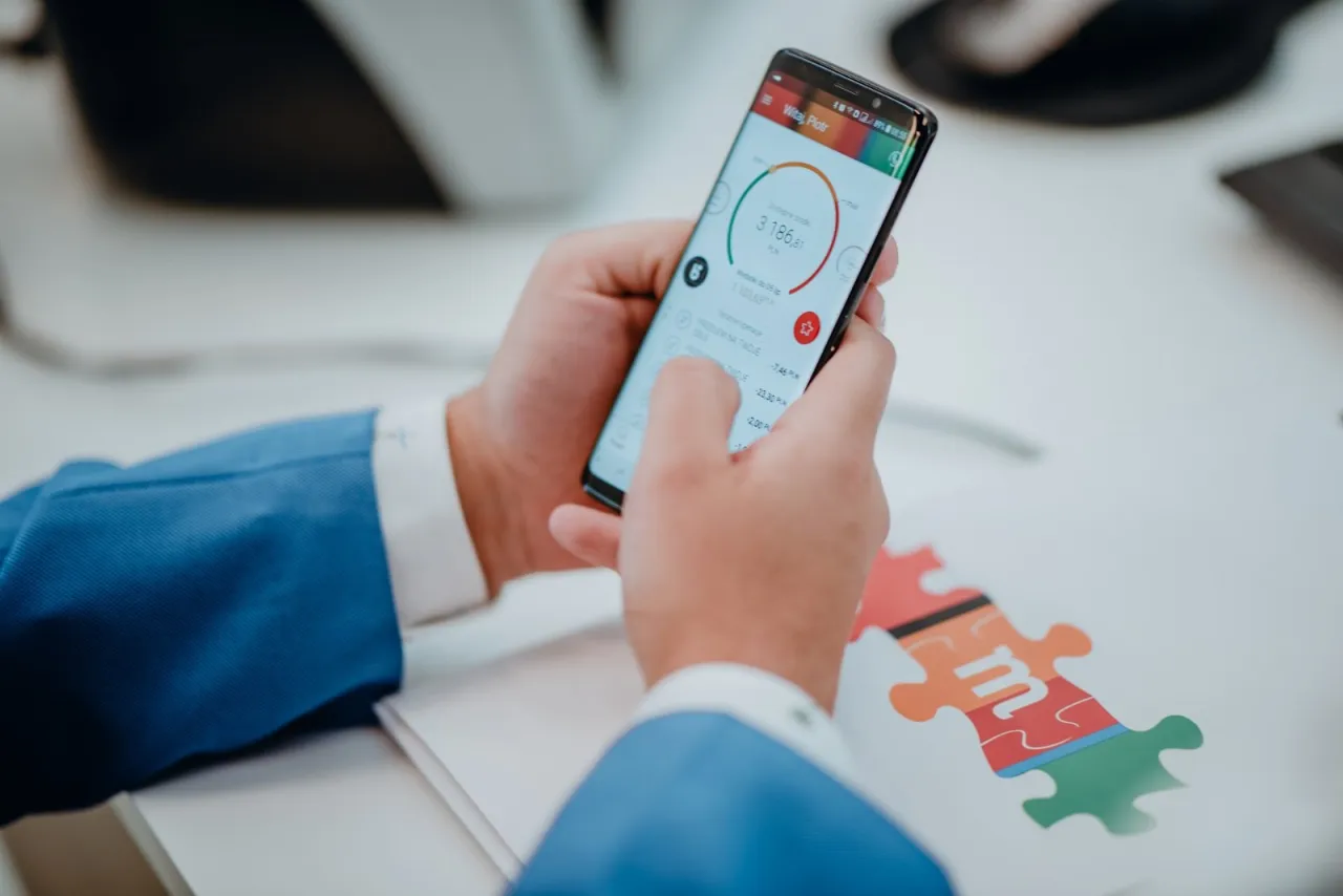 Mężczyzna w niebieskiej marynarce sprawdza aplikację mBank na telefonie, szukając informacji, jak zmienić limity.