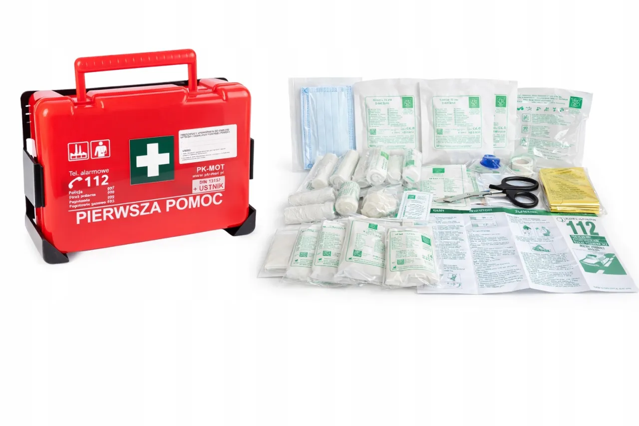 Czerwona apteczka pierwszej pomocy z wyposażeniem, idealna do zakładu pracy. Zawiera m.in. bandaże, plastry, nożyczki i instrukcję.