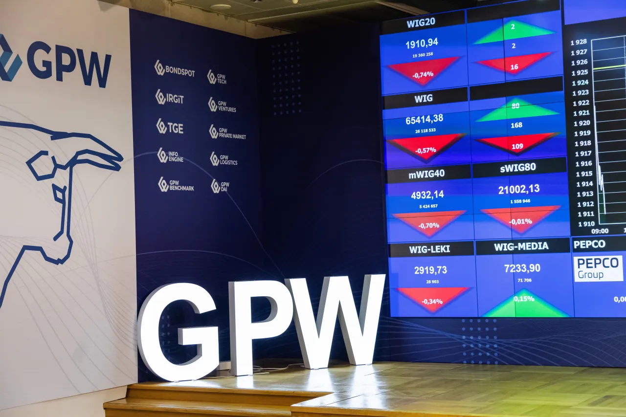 Duże litery GPW i ekran z notowaniami giełdowymi. Od kiedy powstała giełda papier&oacute;w wartościowych w Warszawie? Odpowiedź znajdziesz w historii GPW.