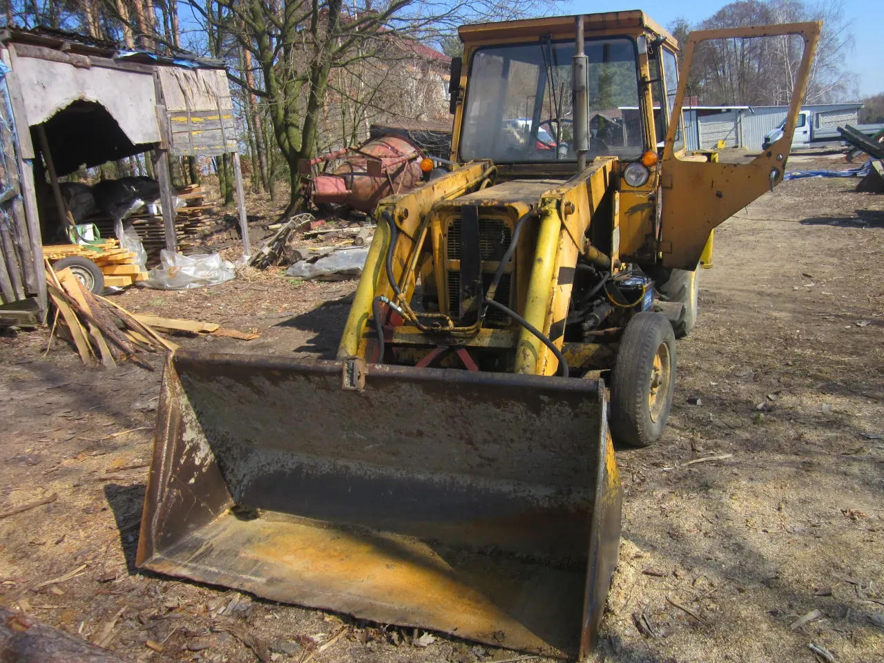 Żółta koparka Ostrówek, trochę zniszczona, stoi na placu budowy. Czy warto kupić koparkę Ostrówek?