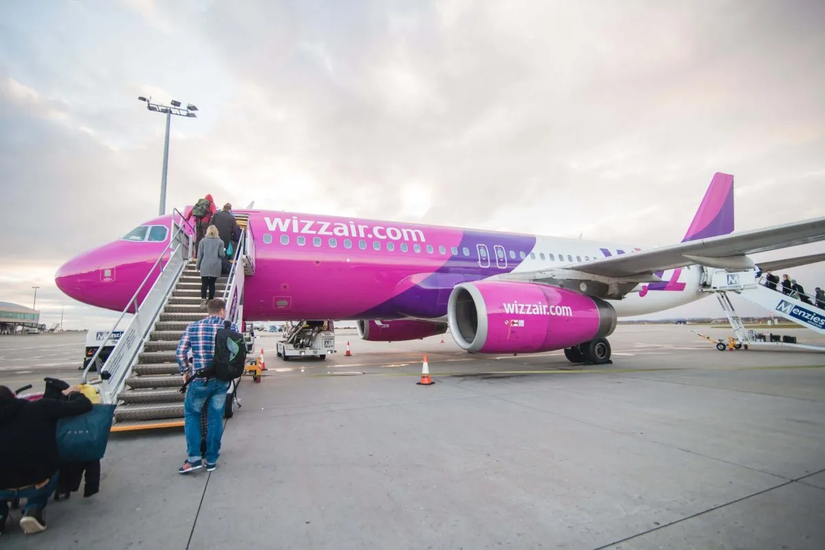 Pasażerowie wsiadają do r&oacute;żowego samolotu Wizz Air. Chcesz wiedzieć, jak zadzwonić do Wizzair za darmo?