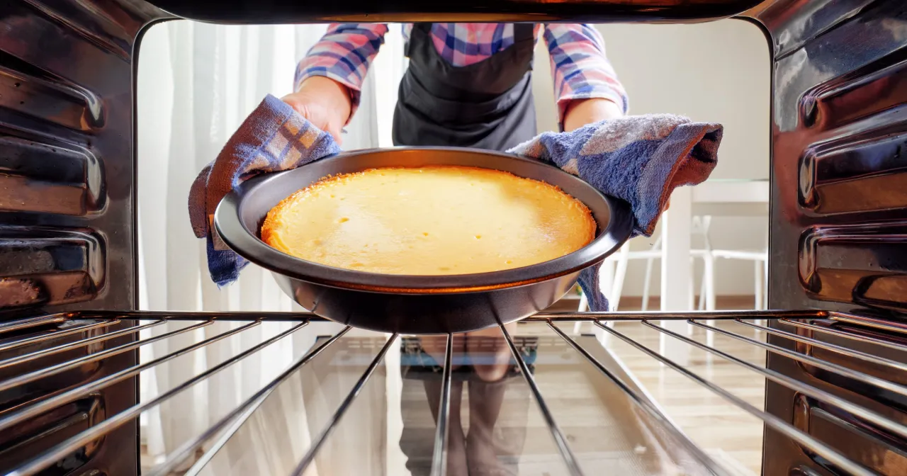 Wyciąganie z piekarnika idealnego sernika. Czas pieczenia i odpowiednia temperatura to klucz do sukcesu.