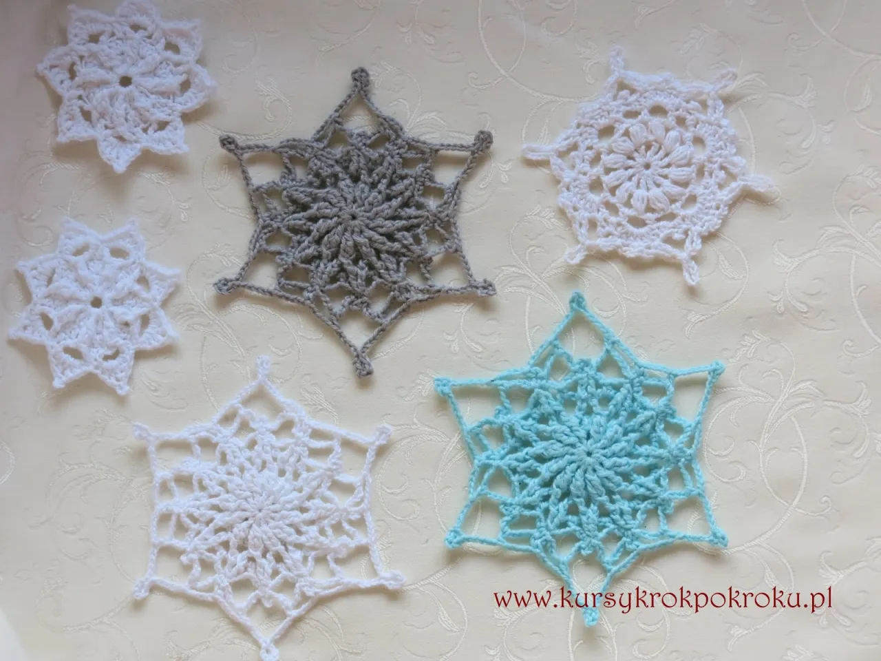 Piękne dekoracje na szydełku w kształcie płatk&oacute;w śniegu. Białe, szare i błękitne ozdoby tworzą zimową atmosferę.