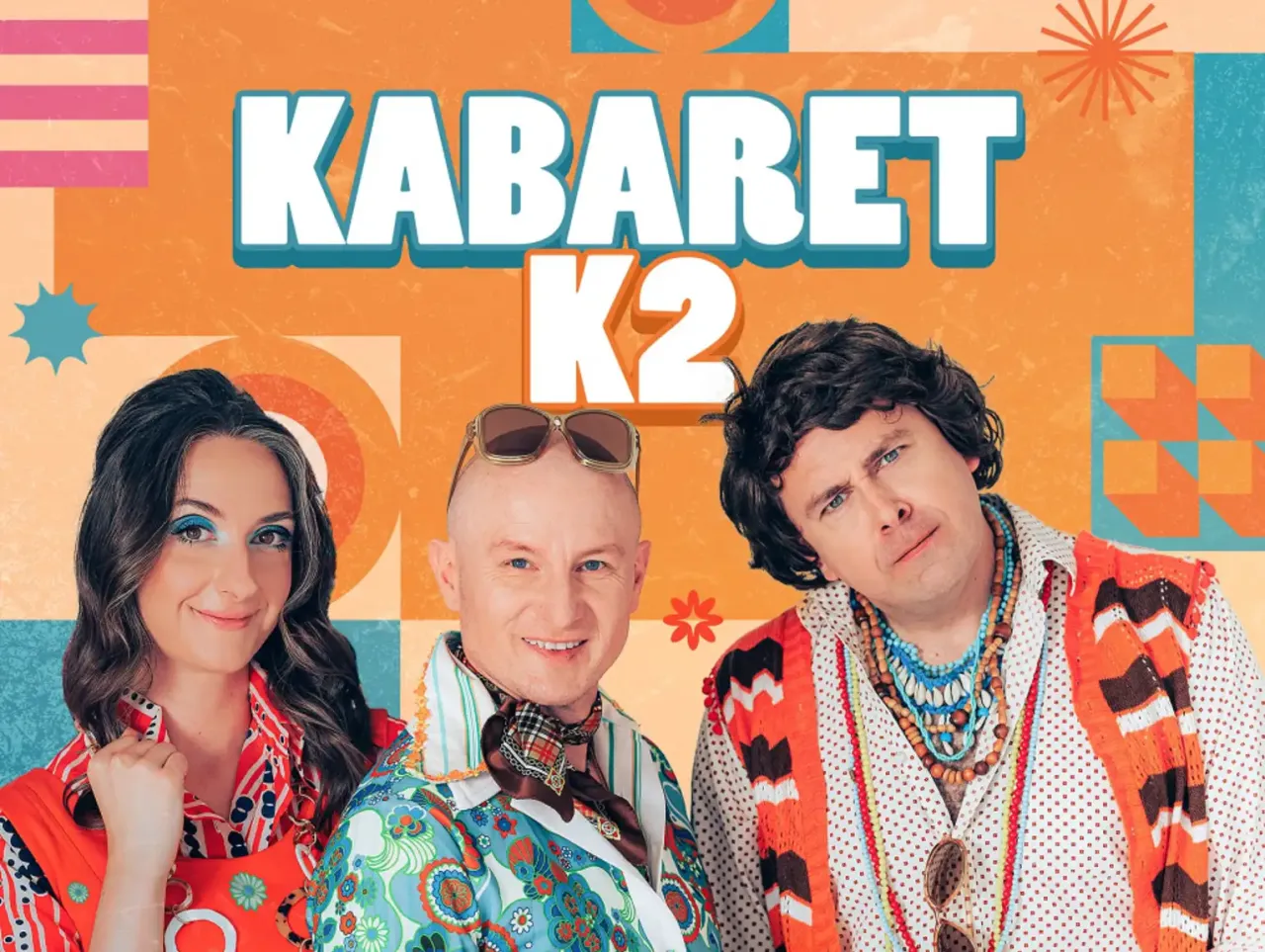 Trzech artyst&oacute;w w kolorowych strojach, z napisem KABARET K2.