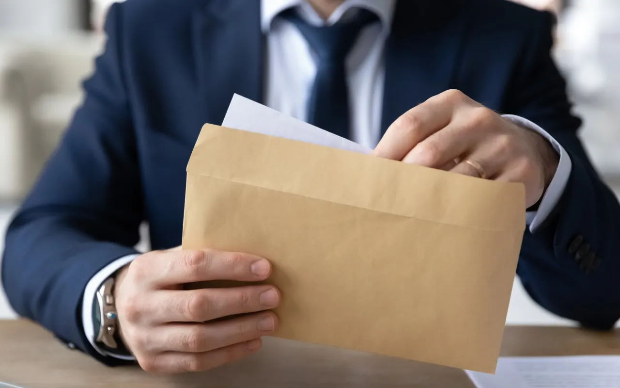 Mężczyzna w garniturze wkłada dokumenty do brązowej koperty. Czy odpowiedź na pozew doręcza się pełnomocnikowi?