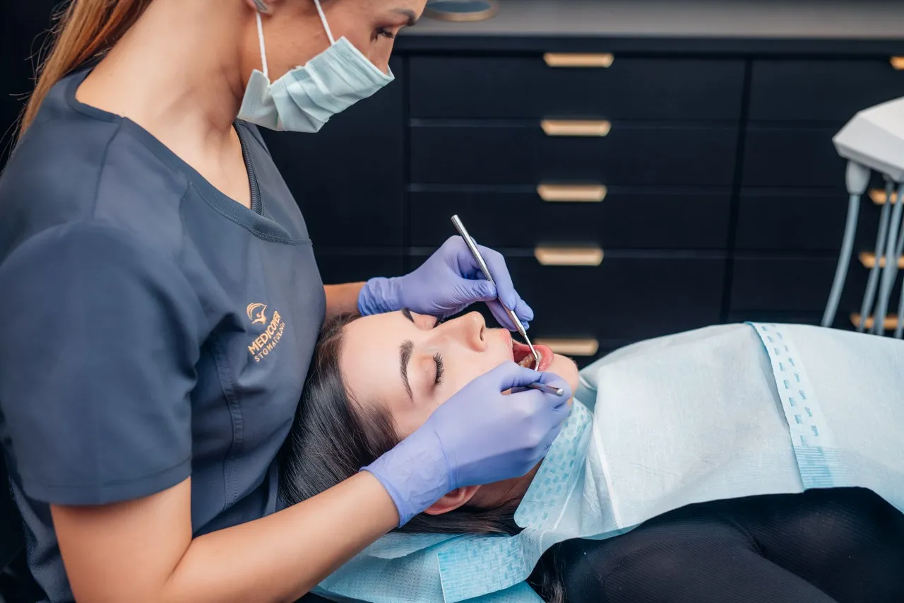 Dentysta w Koninie pomaga pacjentce, kt&oacute;ra przyszła z b&oacute;lem zęba.