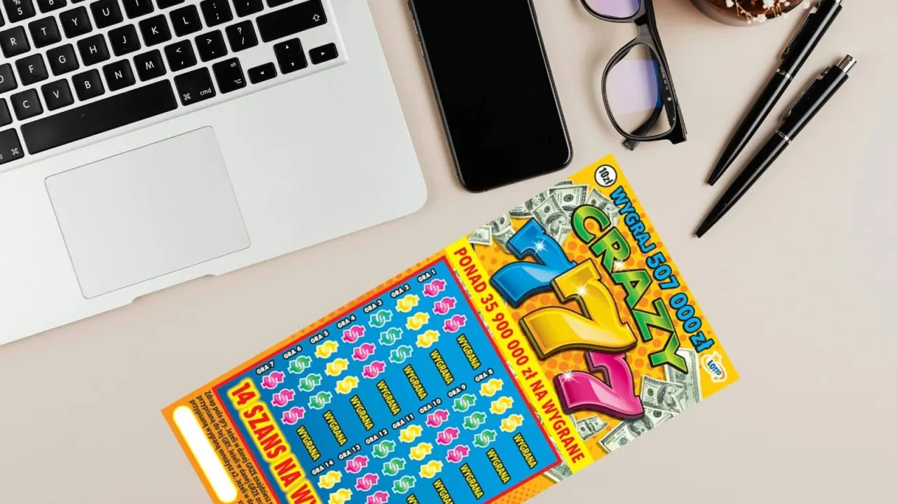 Zdrapki lotto, gdzie kupić? Na biurku obok laptopa leży zdrapka 