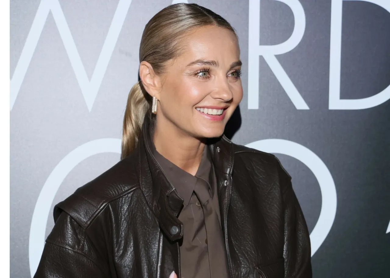 Uśmiechnięta kobieta w brązowej sk&oacute;rzanej kurtce, kt&oacute;ra wygląda na to, że jest jej ulubionym elementem garderoby.