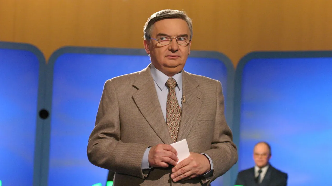 Tadeusz Sznuk, prowadzący jeden z dziesięciu, w beżowej marynarce i krawacie, trzyma kartkę.