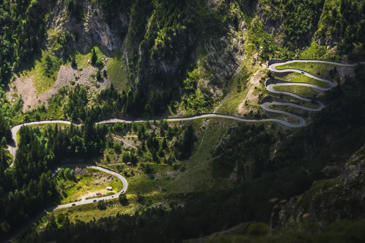 Kręta droga wije się przez zielone zbocza, ukazując, jakie to g&oacute;ry Pireneje w Hiszpanii.