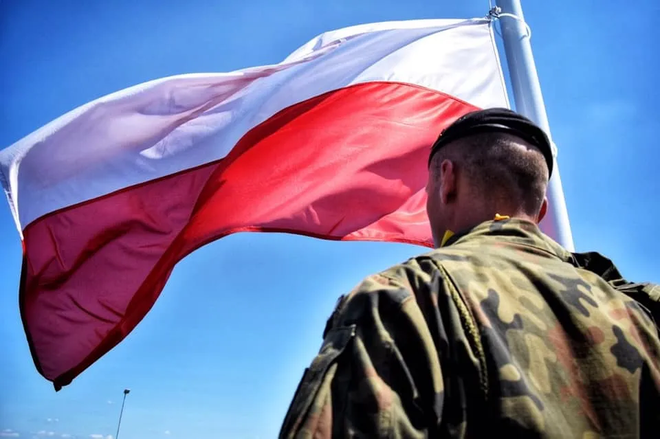 Polska flaga na tle żołnierzy Wojska Polskiego