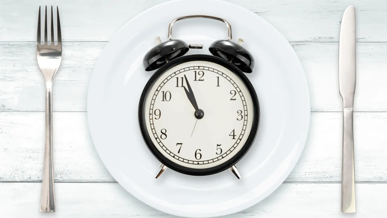 Post przerywany ile schudłam: budzik na talerzu, widelec i n&oacute;ż czekają na posiłek.