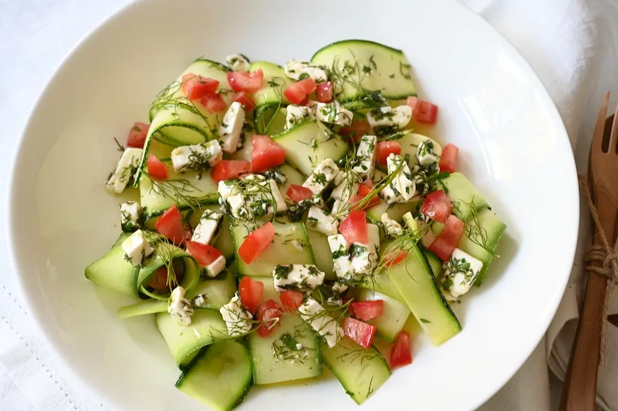 appetitlicher roher Zucchini-Salat in einer Sch&uuml;ssel mit Dressing
