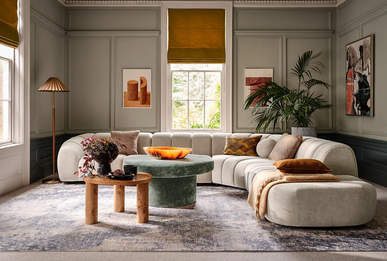 Elegancki salon z zakrzywioną sofą, stolikami i lampą podłogową. Idealne jakie oświetlenie do pokoju, by stworzyć przytulną atmosferę.