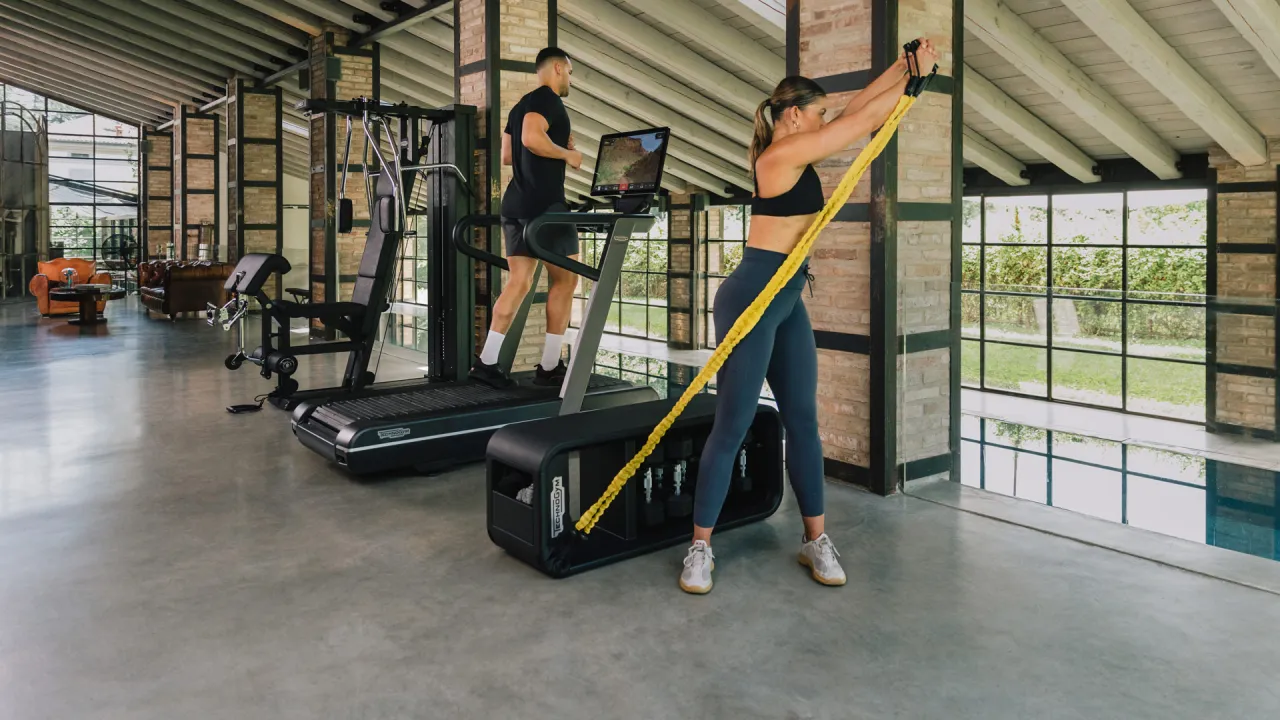 Para ćwiczy w domu. On na bieżni, ona z gumą. Trening w domu może być efektywny, niezależnie od tego, ile powinien trwać.