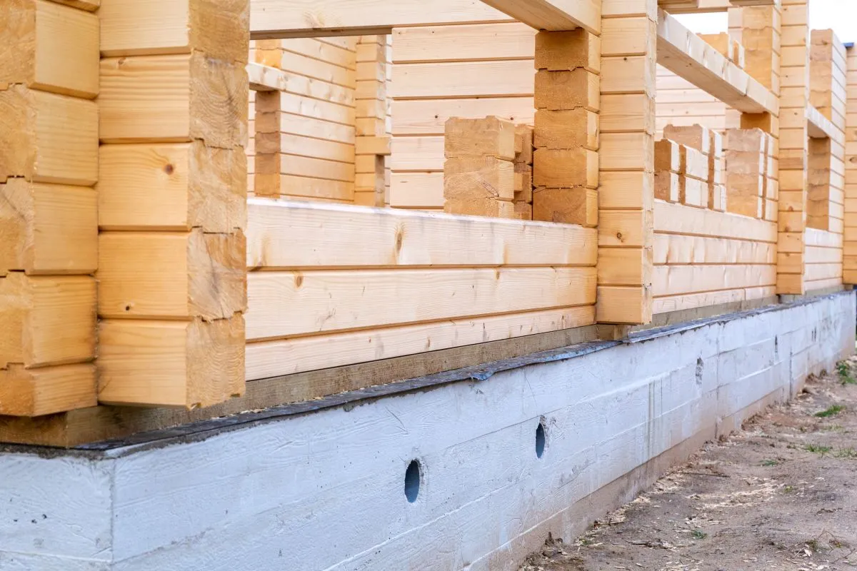 Budowa domu z bali 35m2. Fundament i ściany z drewnianych bali w trakcie budowy.