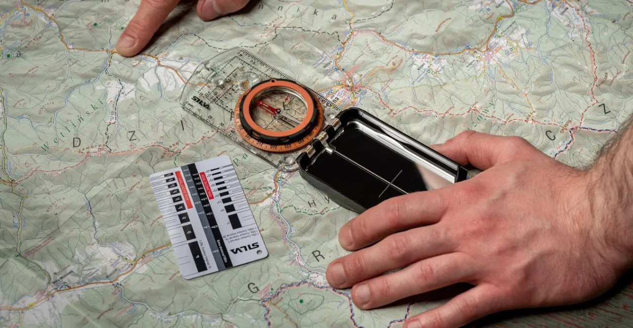 osoba orientująca mapę kompasem w terenie