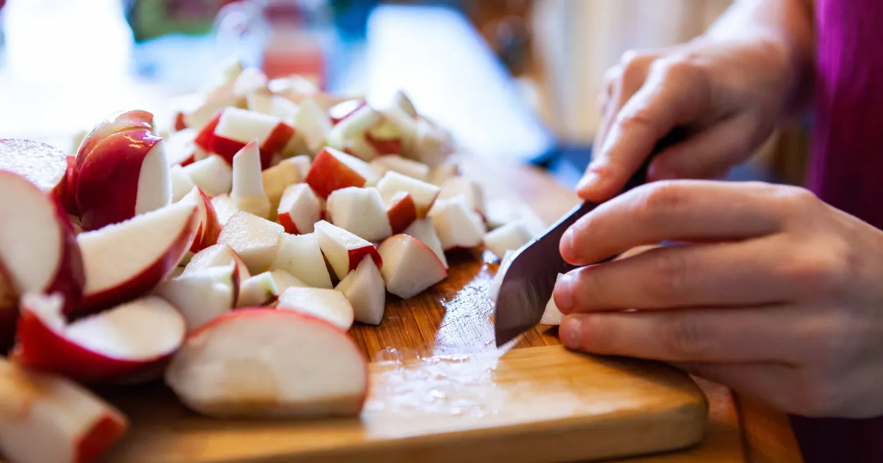 Ręce kroją jabłka na desce. Czy konie mogą jeść jabłka? Tak, to zdrowy przysmak dla koni.