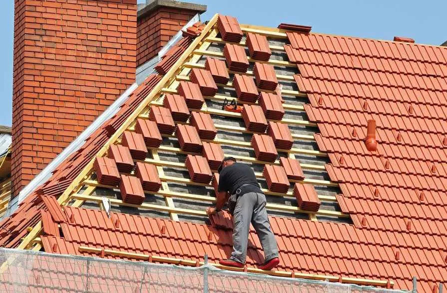 dekarz pracujący na dachu z dachówką ceramiczną