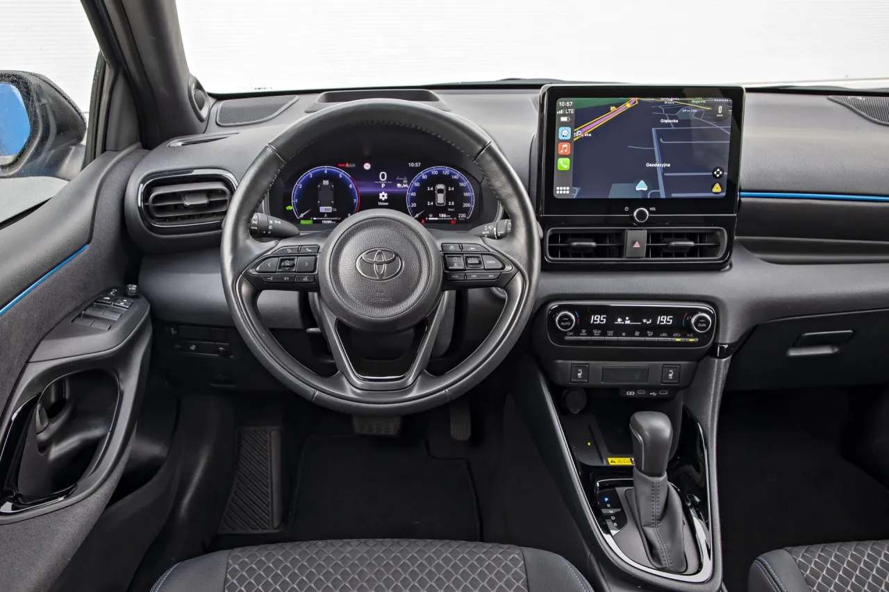 Wnętrze Toyoty Yaris Hybrid: kierownica, ekran nawigacji, panel klimatyzacji. Zastanawiasz się, ile kosztuje Toyota Yaris Hybrid?