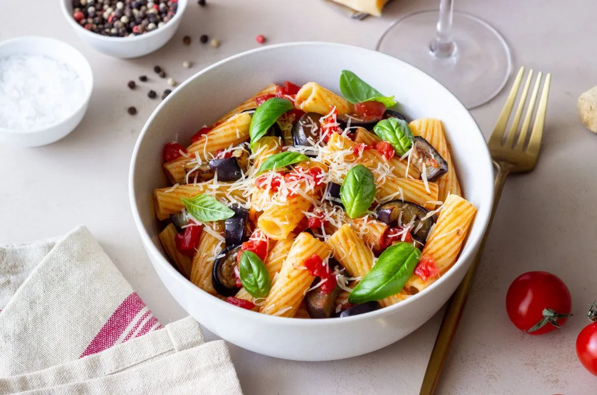 Pyszne danie z makaronu rigatoni z bakłażanem, pomidorami i bazylią. Idealne do przygotowania według przepisu Pasta alla Norma.