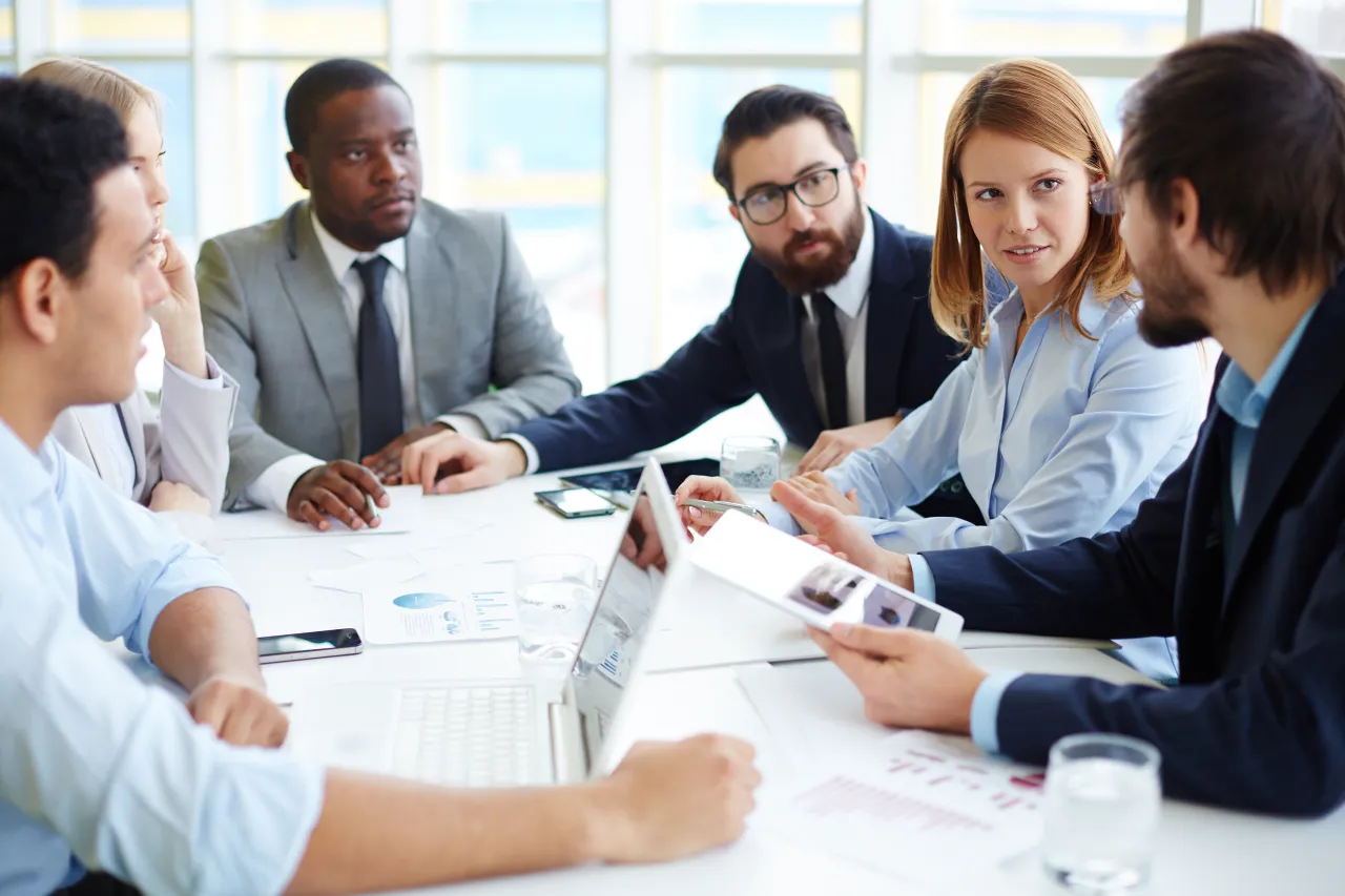 Zespół dyskutuje o absolutorium co to znaczy, analizując dokumenty i dane na laptopie i tablecie.
