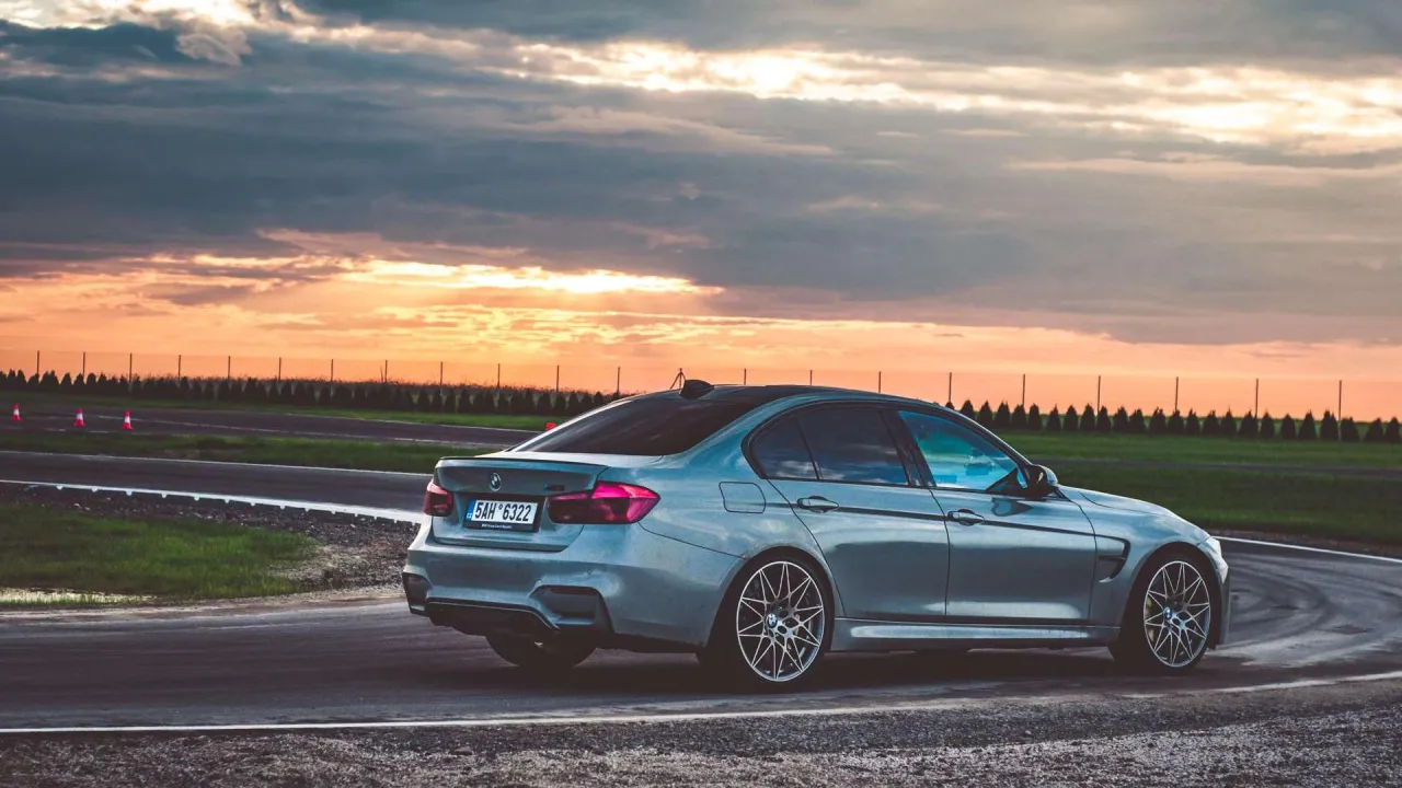 Srebrne BMW M3 F80 na torze wyścigowym podczas zachodu słońca.