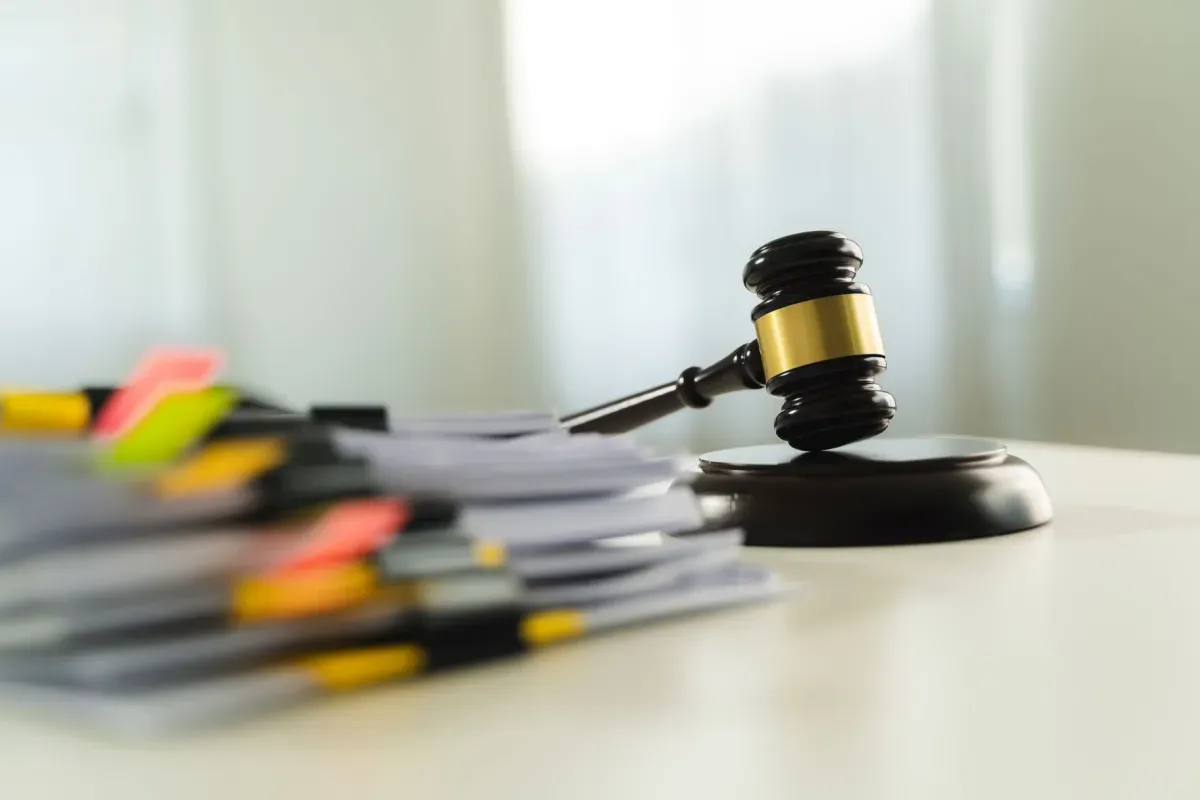 Młotek sędziowski i stos dokumentów z kolorowymi zakładkami. Czy odpowiedź na pozew doręcza się pełnomocnikowi?
