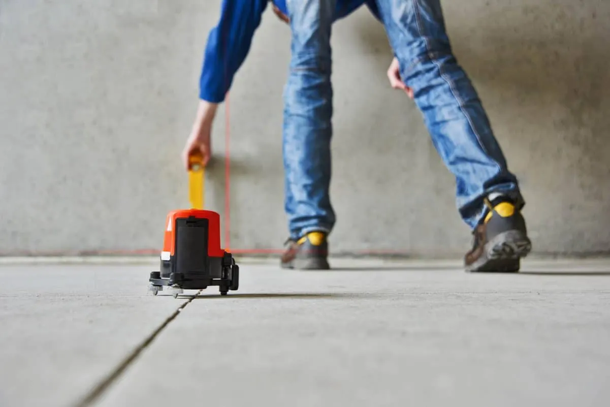 Wykorzystanie poziomicy laserowej do precyzyjnego wyznaczenia linii, kluczowe przy pracach jak zrobić wylewkę w garażu.