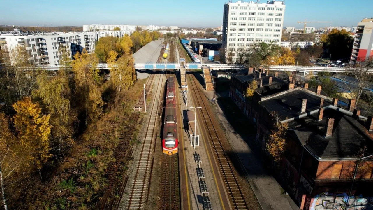 Pociąg na torach między blokami mieszkalnymi a starymi budynkami przemysłowymi. Jesień w Katowicach i Sosnowcu.
