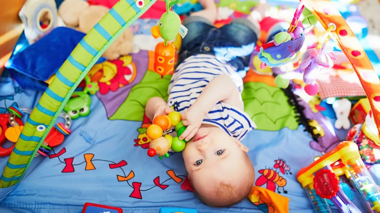 szczęśliwe niemowlę na kolorowej macie edukacyjnej