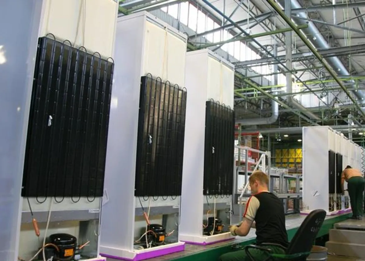 Linia produkcyjna lod&oacute;wek Indesit. Pracownicy montują komponenty, tworząc sprzęt AGD.