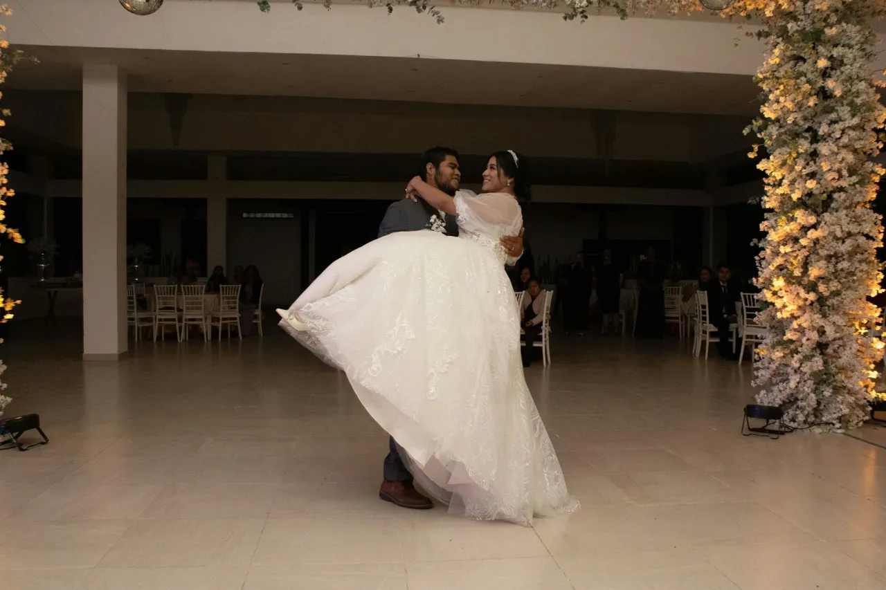 Pan młody unosi pannę młodą w tańcu. Wygląda to jakbym leciał na wesele, pełne miłości i radości.