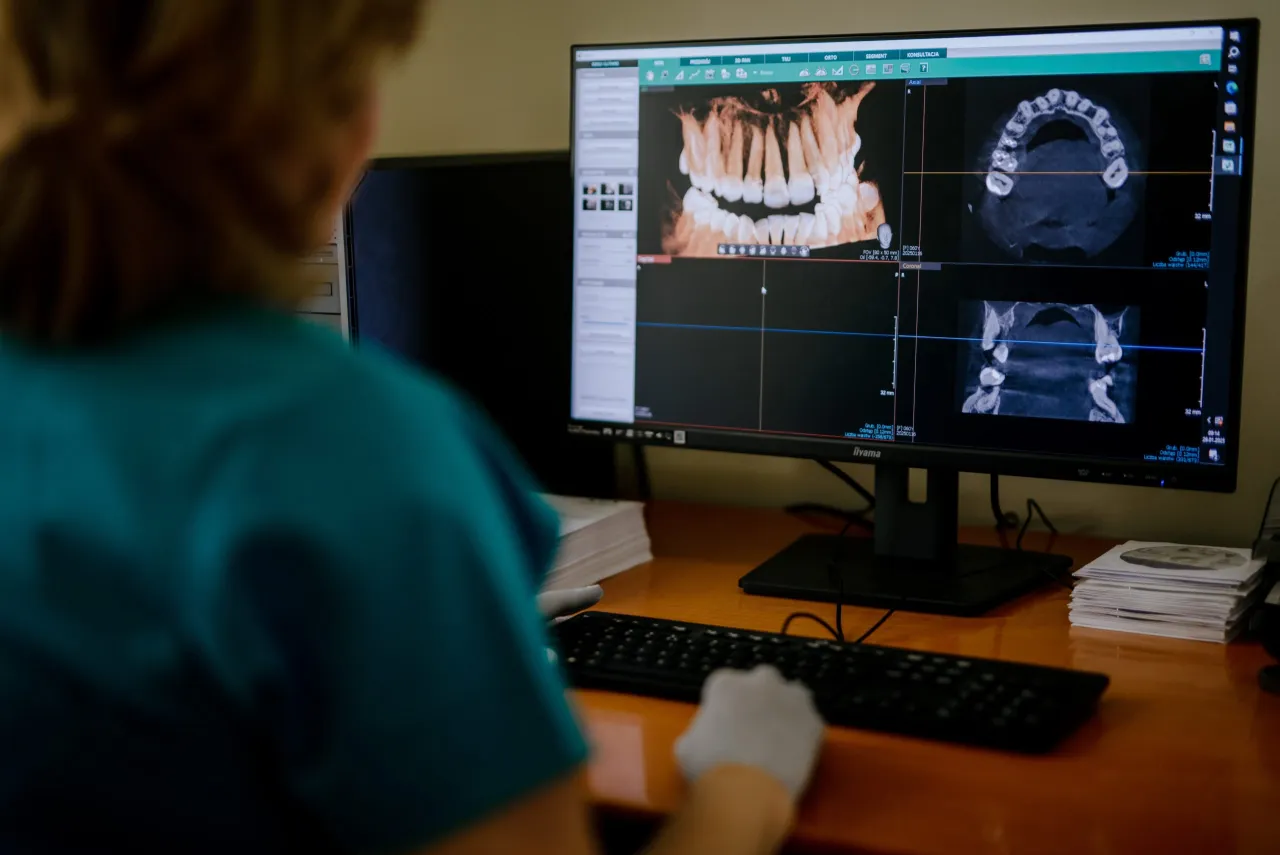 Ortodonta analizuje skany zębów na monitorze, ucząc się, jak zostać ortodontą.
