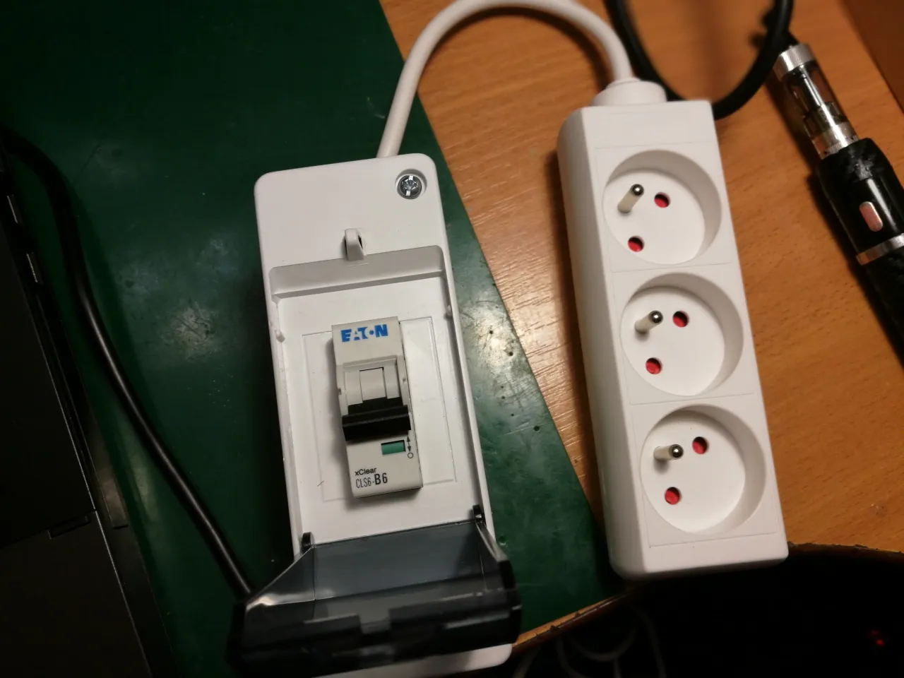 Wyłącznik nadprądowy Eaton i listwa zasilająca z trzema gniazdami, gotowe do podłączenia urządzeń. Prąd w obu przewodach jest bezpieczny.