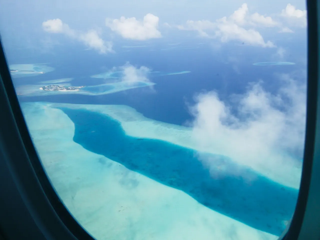 Widok z samolotu na turkusowe wody i atole Malediw&oacute;w. Zastanawiasz się, ile trwa lot na Malediwy?