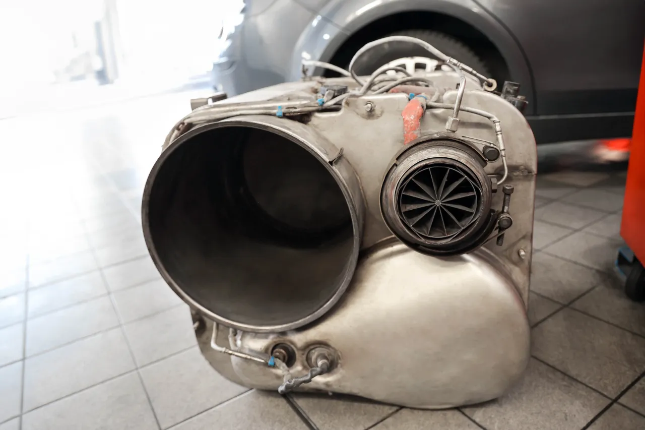 Metalowy element układu wydechowego, prawdopodobnie turbosprężarka lub katalizator, leży na podłodze. Brak DPF to kosztowna kara.