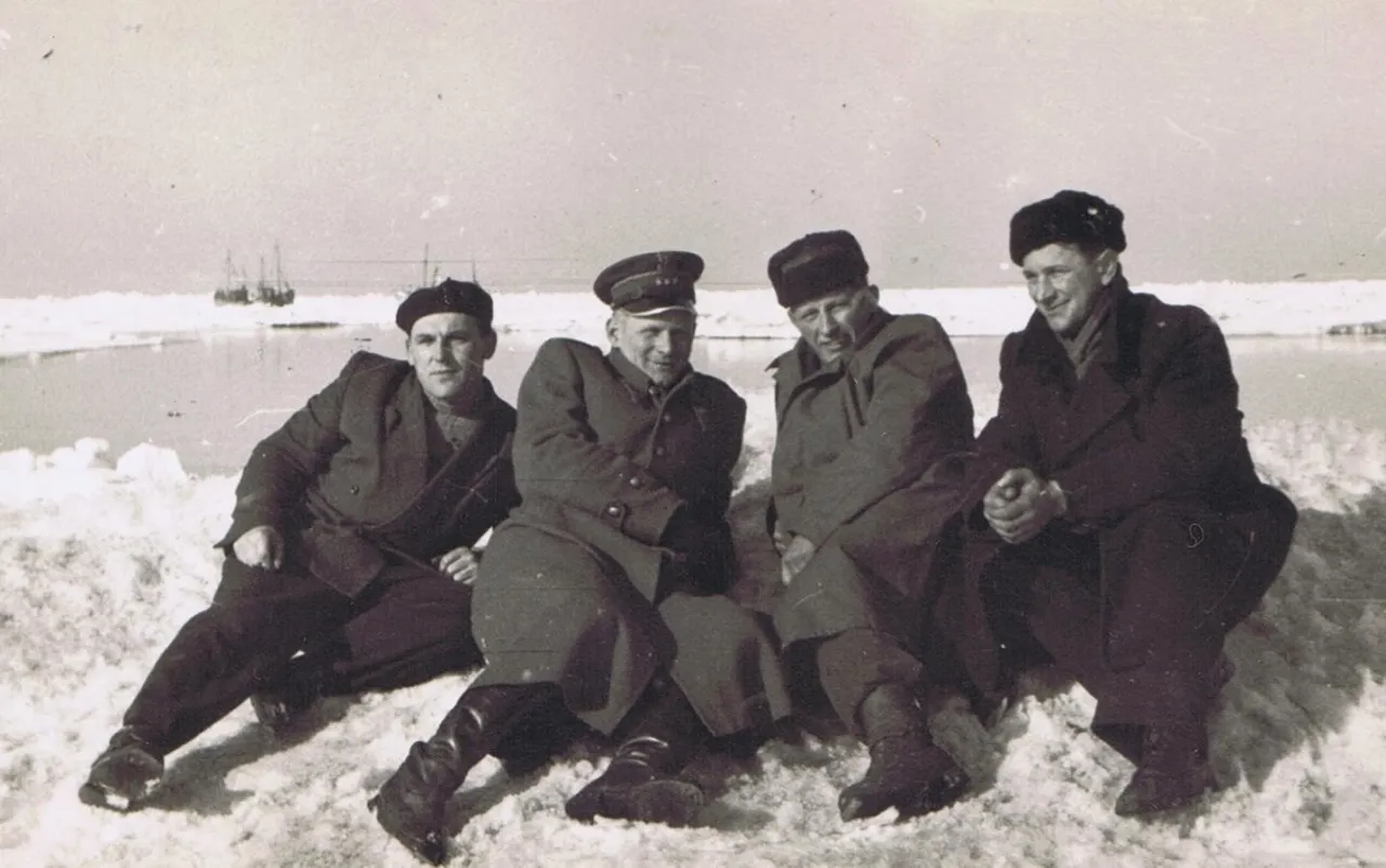 Czterech mężczyzn w zimowych ubraniach siedzi na lodzie, gdy zamarzło Morze Bałtyckie. W tle widać statki.