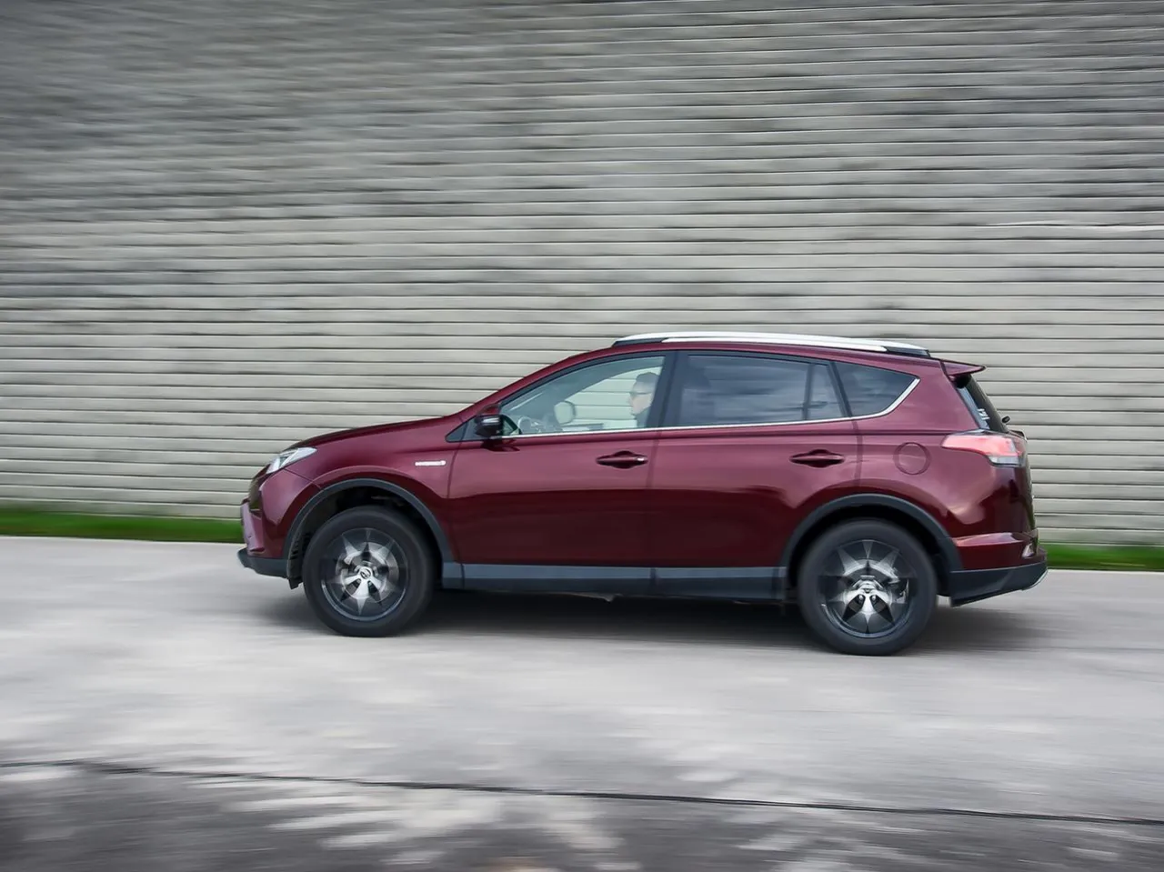 Czerwona Toyota RAV4 w ruchu, zastanawiasz się, ile pali? Ten SUV świetnie wygląda na drodze.