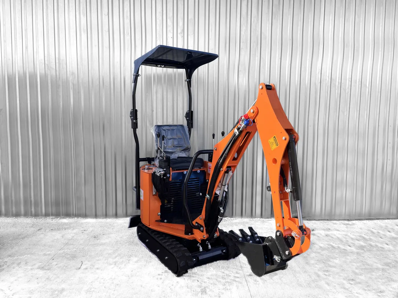 Pomarańczowa minikoparka z gąsienicami i łyżką. Zastanawiasz się, ile pali minikoparka na godzinę?