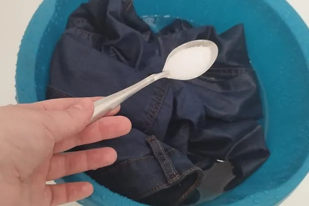 kobieta sprawdza czy jeansy farbują pocierając je białą szmatką